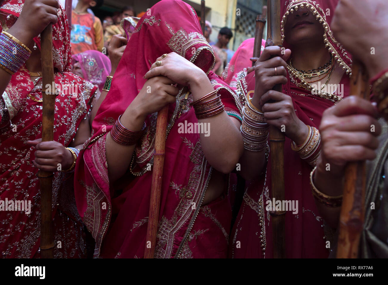 A Barsana Holi in un tradizionale confronto, un gruppo di donne colpite con canne di bambù sugli scudi che proteggono gli uomini. Foto Stock