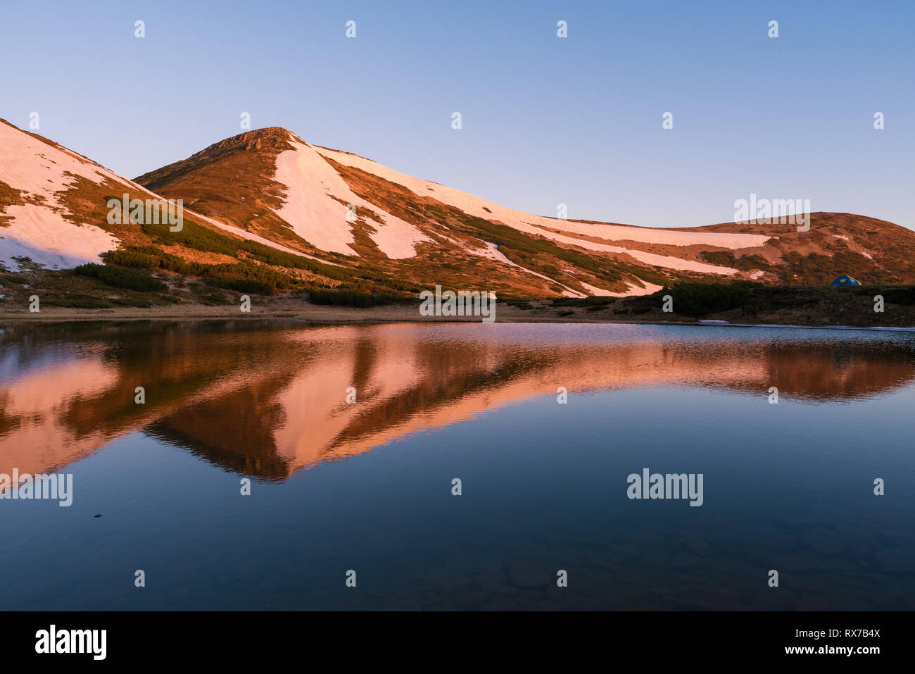 Lago di montagna in primavera. Paesaggio di montagna al mattino. L'ultima neve sulle colline. La riflessione del cielo in acqua. Carpazi, Ucraina, Euro Foto Stock