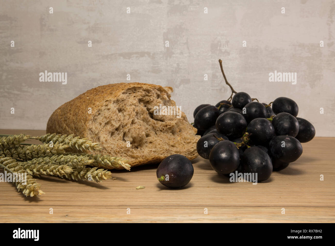 Un pane di frumento e shock di grano con uve rosse come la pasqua lst cena sullo sfondo Foto Stock