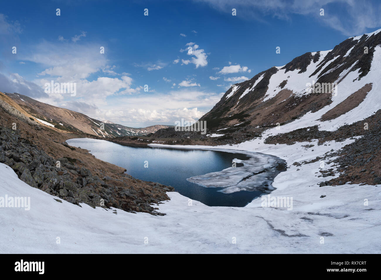 La molla del paesaggio. Lago di montagna con ghiaccio e neve sulla riva. Nuvoloso Giorno. Carpazi, Ucraina, Europa Foto Stock