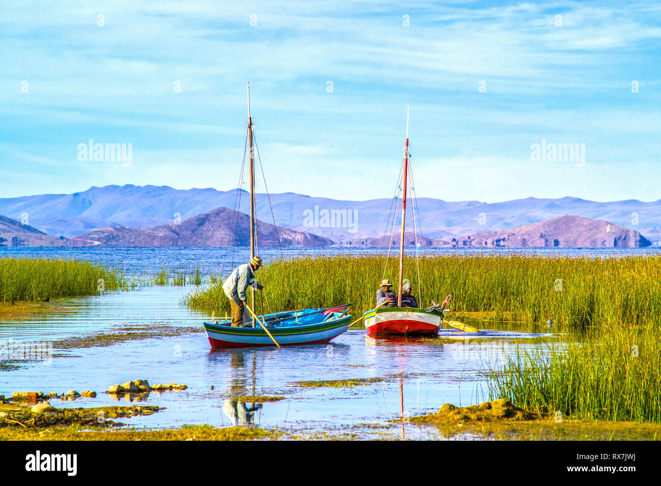Il lago Titicaca; BOLIVIA, due piccole imbarcazioni con la gente del luogo di atterraggio in una baia, racchiuso da reed Foto Stock