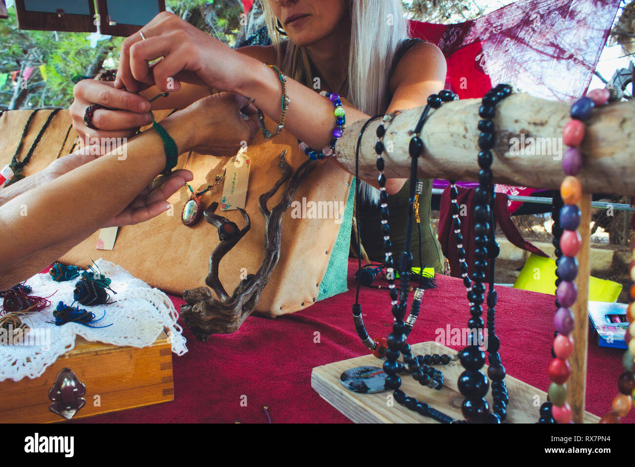 Una donna in casa di vendita gioielli artigianali da un mercato in stallo presso un festival hippy Foto Stock