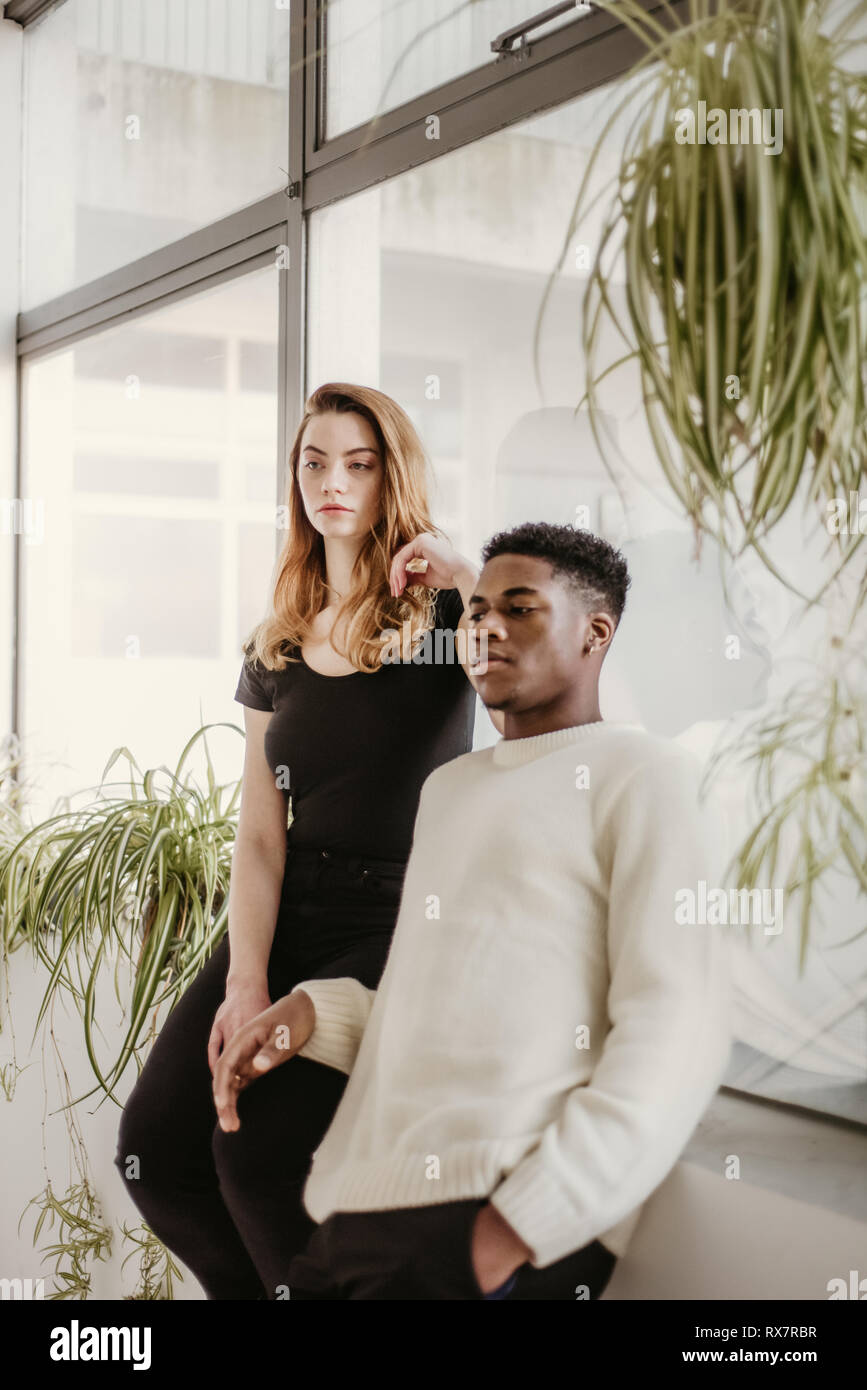 Una buona ricerca e coppia giovane pone con gli uni accanto agli altri e guardare la fotocamera. Ella è bianca, egli è nero hanno facce gravi Foto Stock