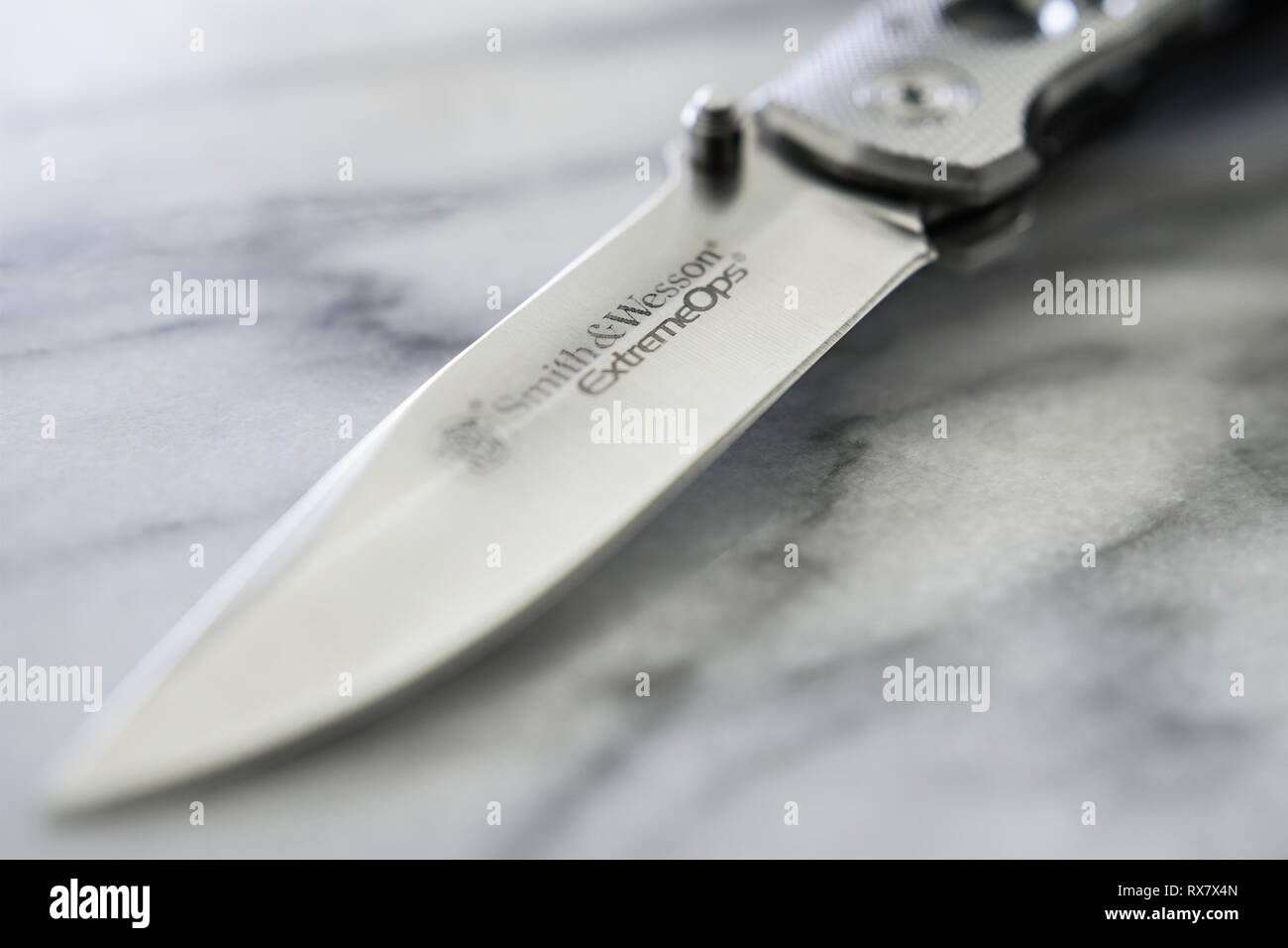 Una vista ravvicinata della lama di questo S&W coltello pieghevole Extreme Ops, su un marmo superficie trasparente. Foto Stock