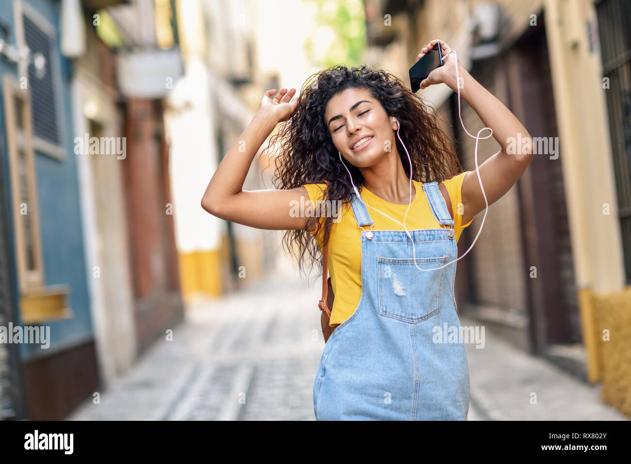 Attraente ragazza africana ascoltando la musica con gli auricolari all'esterno. Foto Stock