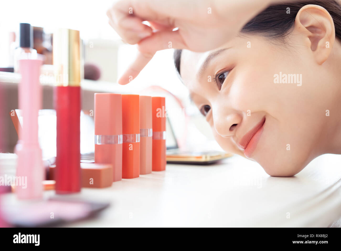 Donna asiatica puntando la scelta di rossetto Foto Stock