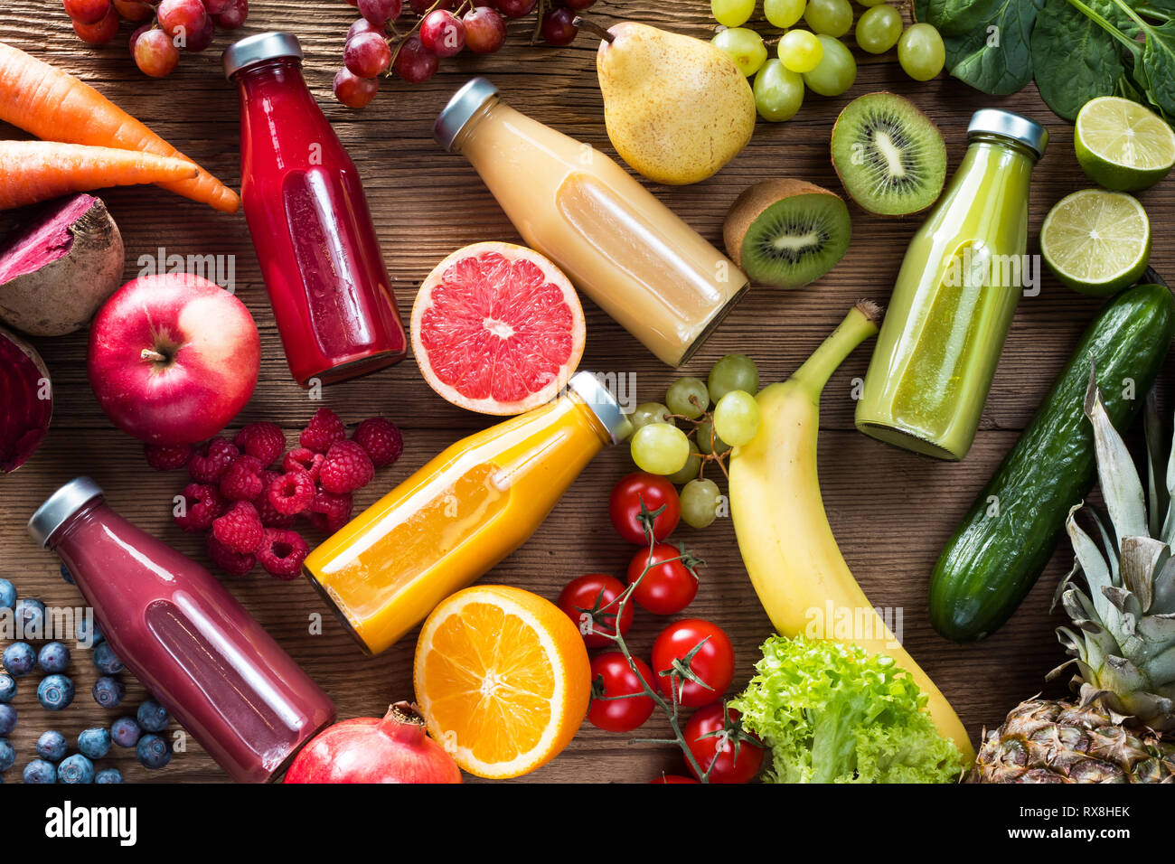Frullati colorati in bottiglie e frutta fresca e verdure su woodentable, vista dall'alto. Foto Stock