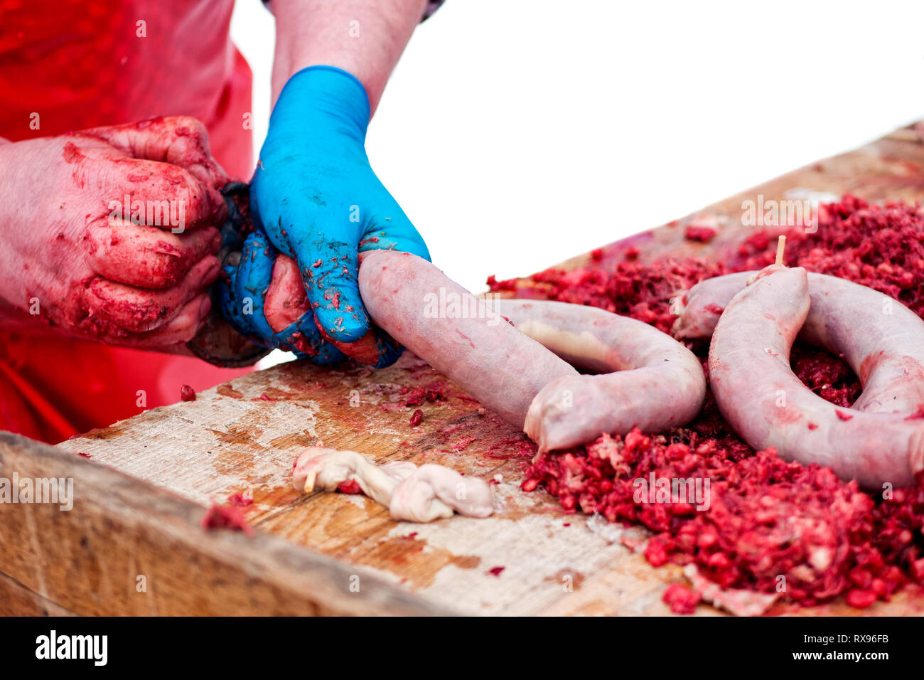 Un uomo salsiccia di riempimento di contenitori con impasto di carne a mano su legno butcher blocco . Foto Stock