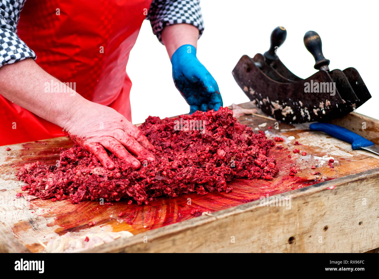 Un uomo di carne di miscelazione a mano per la carne di maiale salsicce di sangue sulla macelleria in legno blocco . Foto Stock