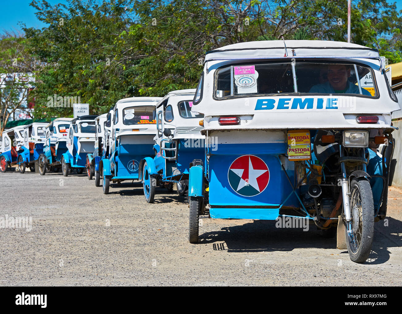 Puerto Princesa City, PALAWAN FILIPPINE: Blu e bianco di tricicli in attesa in linea per i turisti di fronte all'aeroporto Foto Stock