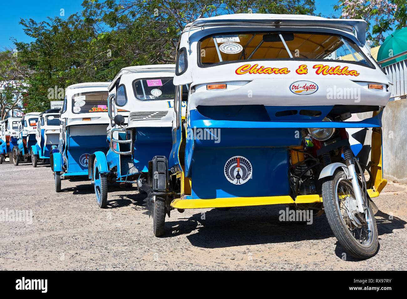 Puerto Princesa City, PALAWAN FILIPPINE: Blu e bianco di tricicli in attesa in linea per i turisti di fronte all'aeroporto Foto Stock