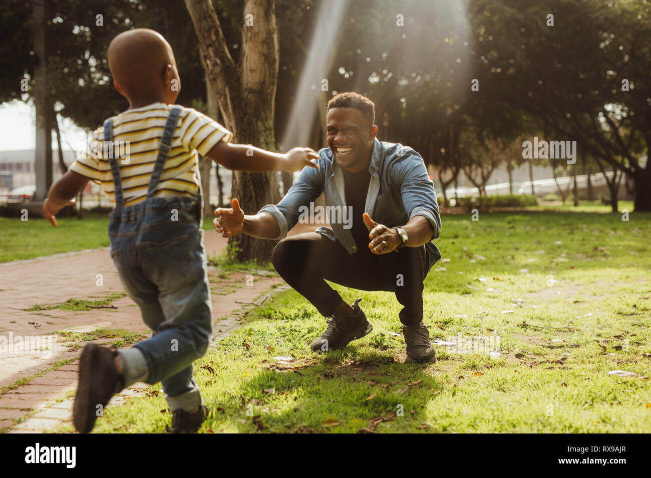 L'uomo accovacciato presso il parco con braccia aperte, con un ragazzo che  corre verso di lui. Figlio in esecuzione in padre di braccia Foto stock -  Alamy