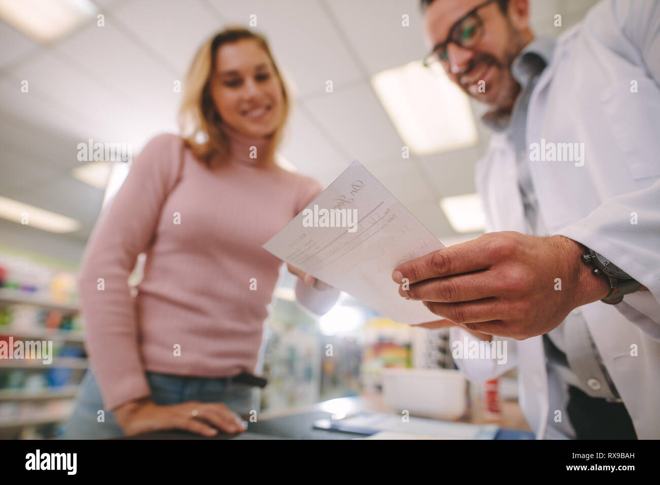 Il farmacista maschio femmina aiuta il cliente a farmacia. Il farmacista di spiegare una prescrizione per il cliente, di concentrarsi su prescrizione medica. Foto Stock