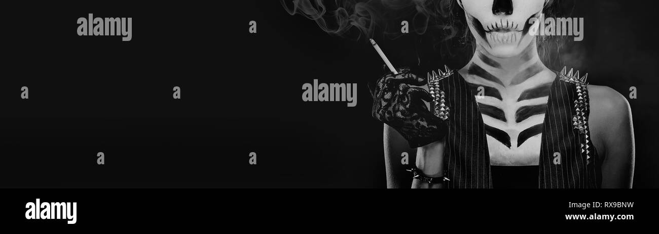 Bianco e nero immagine panoramica donna con scheletro arte viso make-up tenendo il fumo di sigaretta su sfondo nero, concettuale foto, cattiva abitudine Foto Stock
