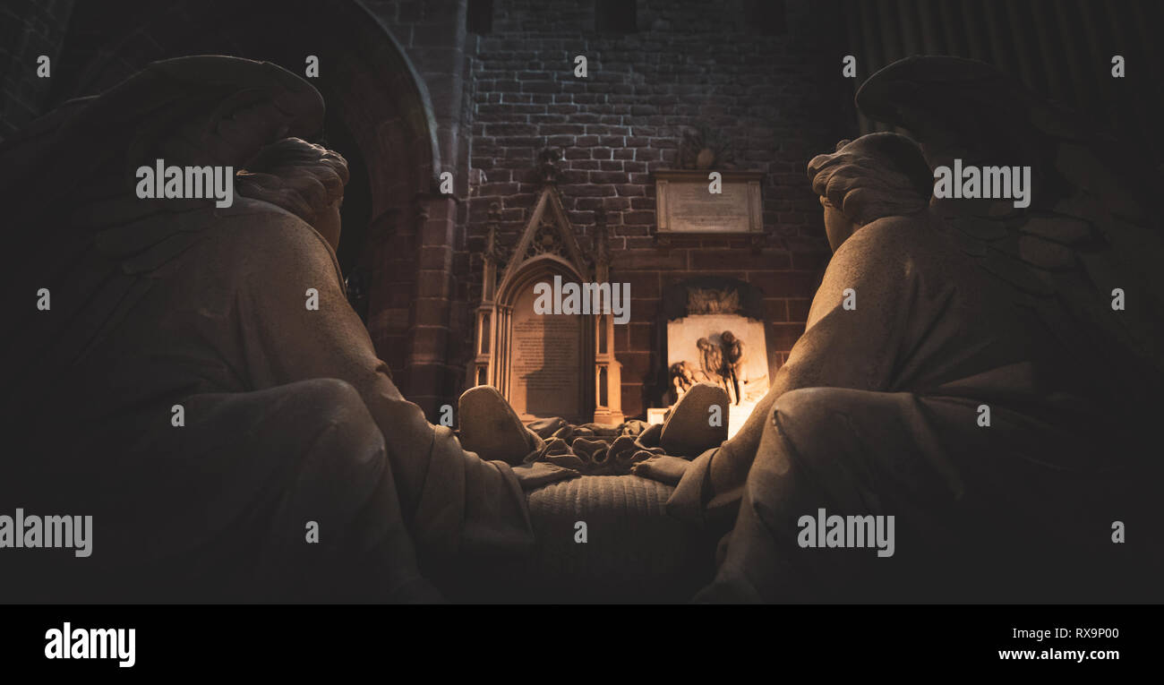 Due statue di angeli sit affacciato su una tomba nella cattedrale di Chester Foto Stock