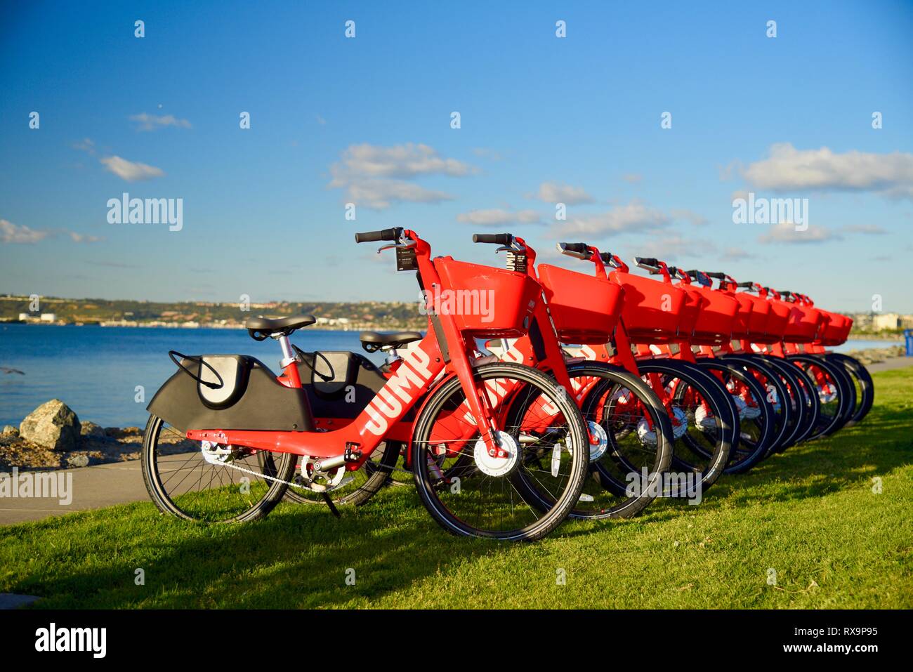 Uber del salto ride-sharing (condivisione bici) rosso, biciclette elettriche (e-bikes) allineati sull'erba su Harbour Island, San Diego, Stati Uniti d'America Foto Stock