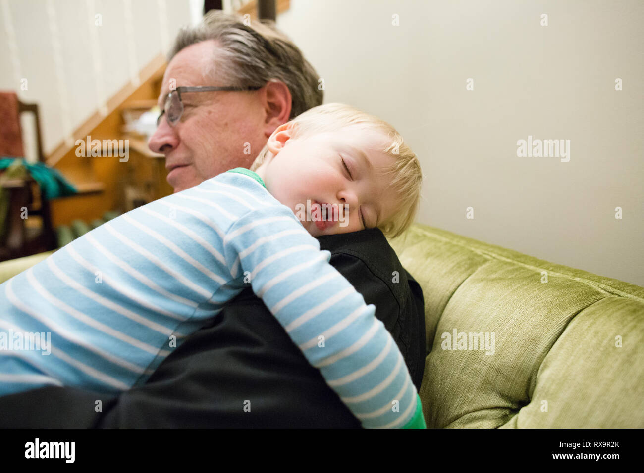 Nonno che trasportano carino nipote dorme sulla spalla a casa Foto Stock