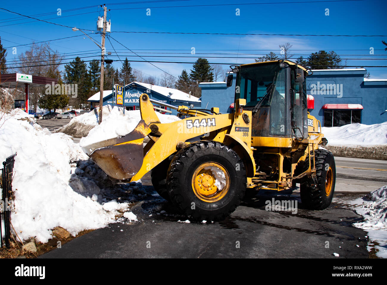 Un John Deere 544H della pala caricatrice gommata neve in movimento da un vialetto in speculatore, NY USA Foto Stock