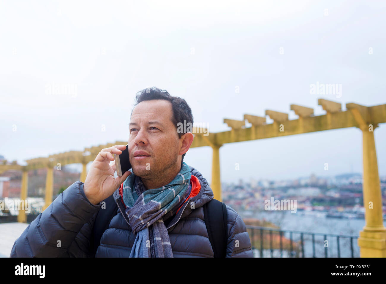 Tourist indossando un abbigliamento caldo rispondendo alle smart phone mentre guarda lontano in città Foto Stock