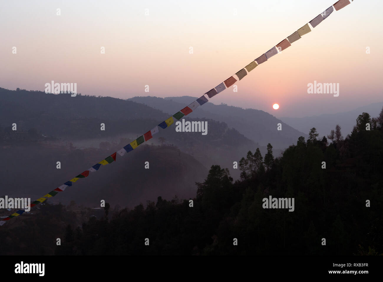 Bandiere di preghiera appeso sulla montagna contro il cielo chiaro durante il tramonto Foto Stock