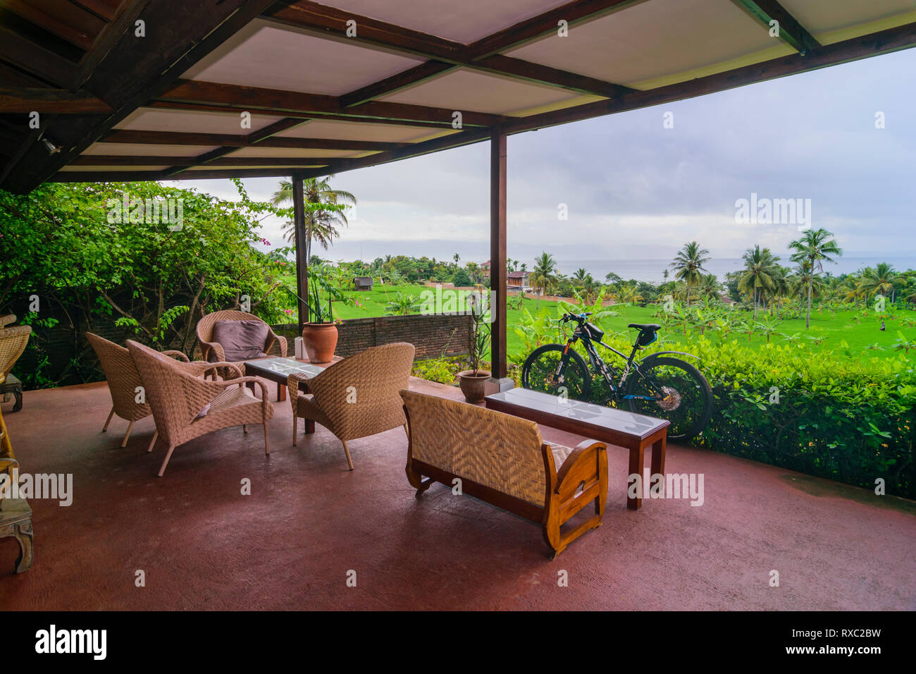 Una veranda dell Hotel in Cisolok, Pelabuhan Ratu affacciato risone nei campi e la baia con bicicletta pronto per effettuare il roaming della zona Foto Stock