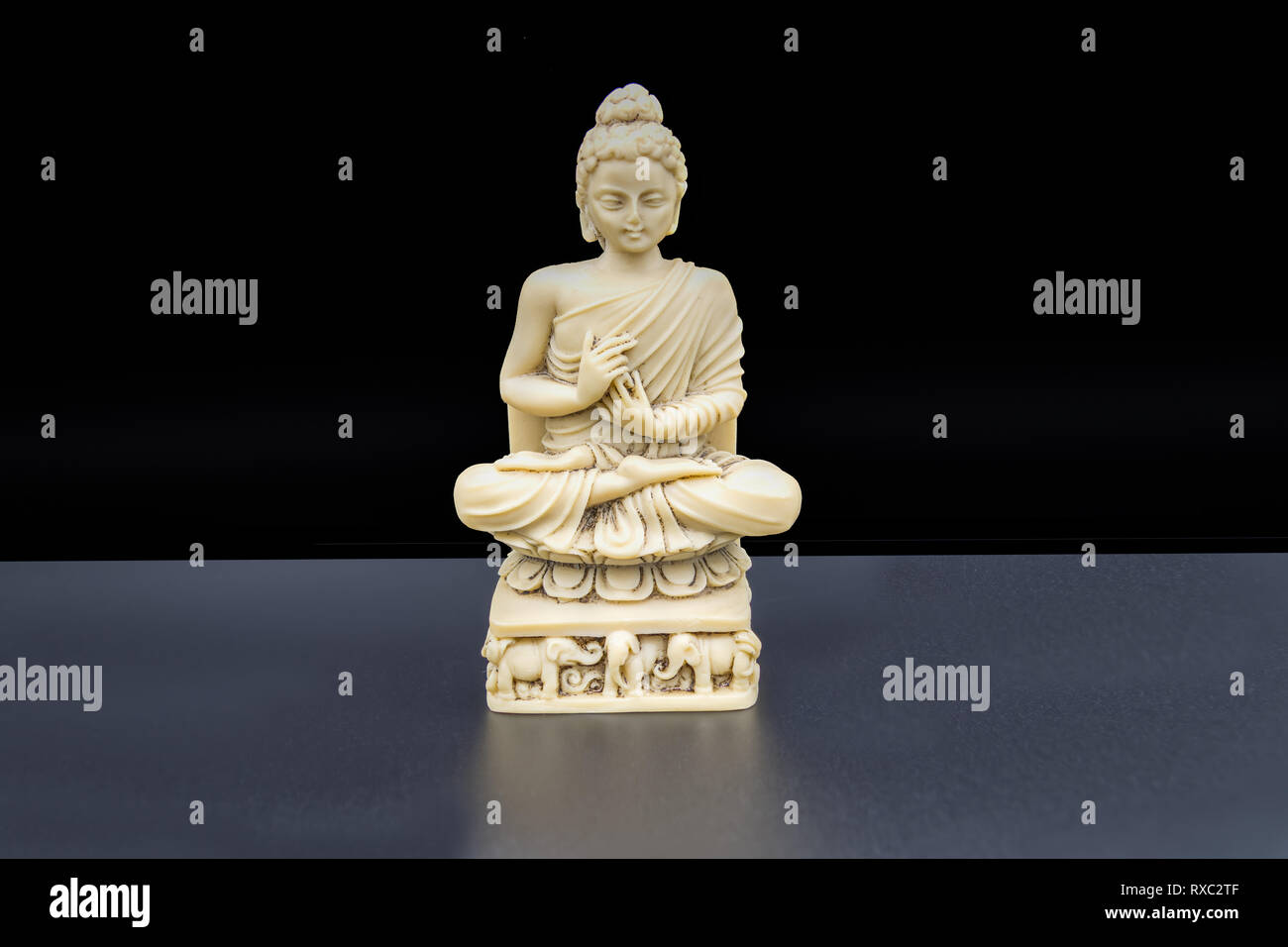 Allenati risolutamente ad essere tutt'uno con pace e armonia. Una statuetta di Buddha seduta in posizione di loto su sfondo nero. Foto Stock