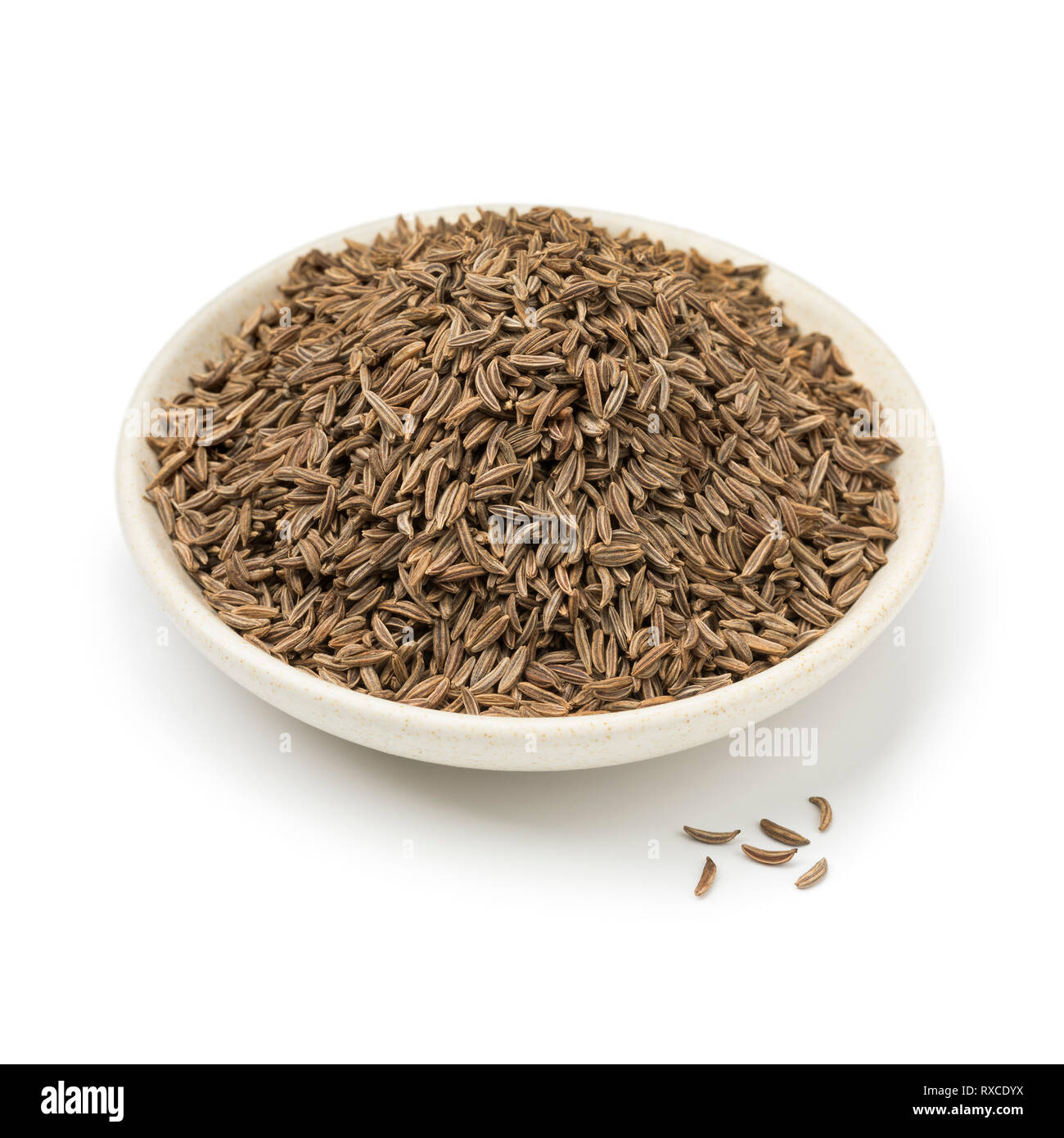 Piatto con organico essiccato di semi di cumino isolati su sfondo bianco Foto Stock