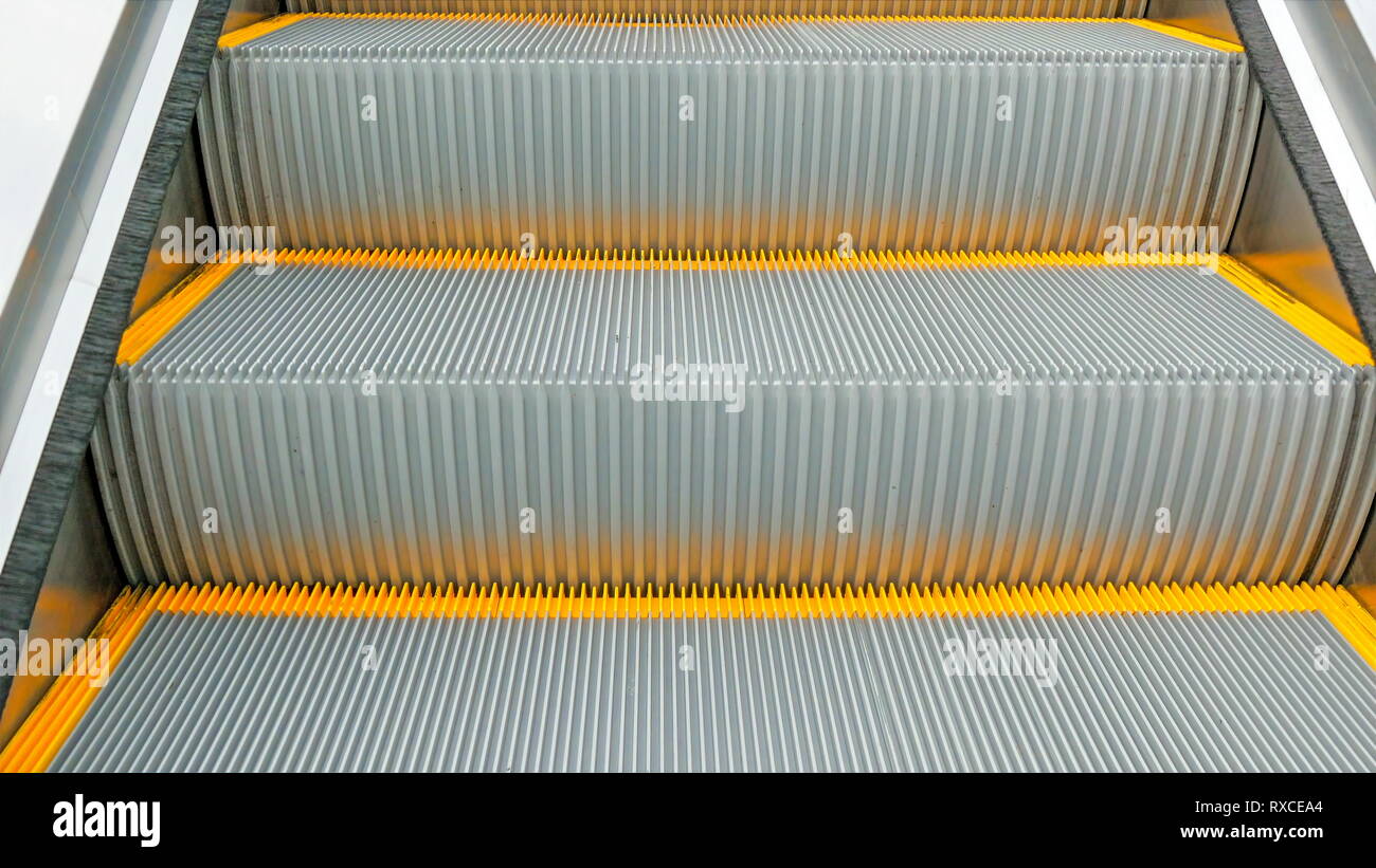 Una scala mobile che va fino a un edificio. Approfondimento delle linee gialle e fasi di escalator Foto Stock