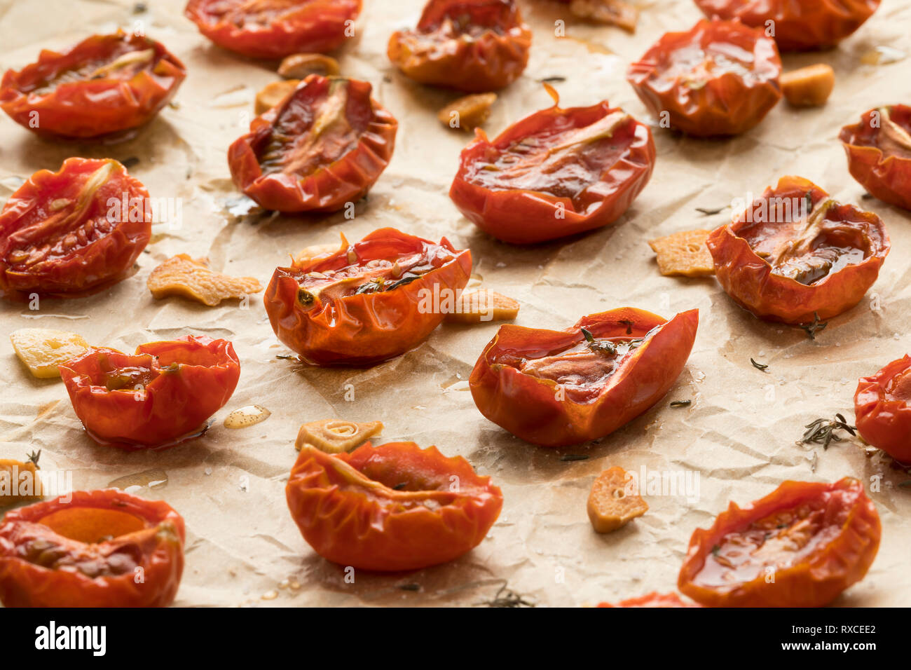 Secco mini arrosto pomodori con fettine di aglio e timo sulla carta da forno close up Foto Stock