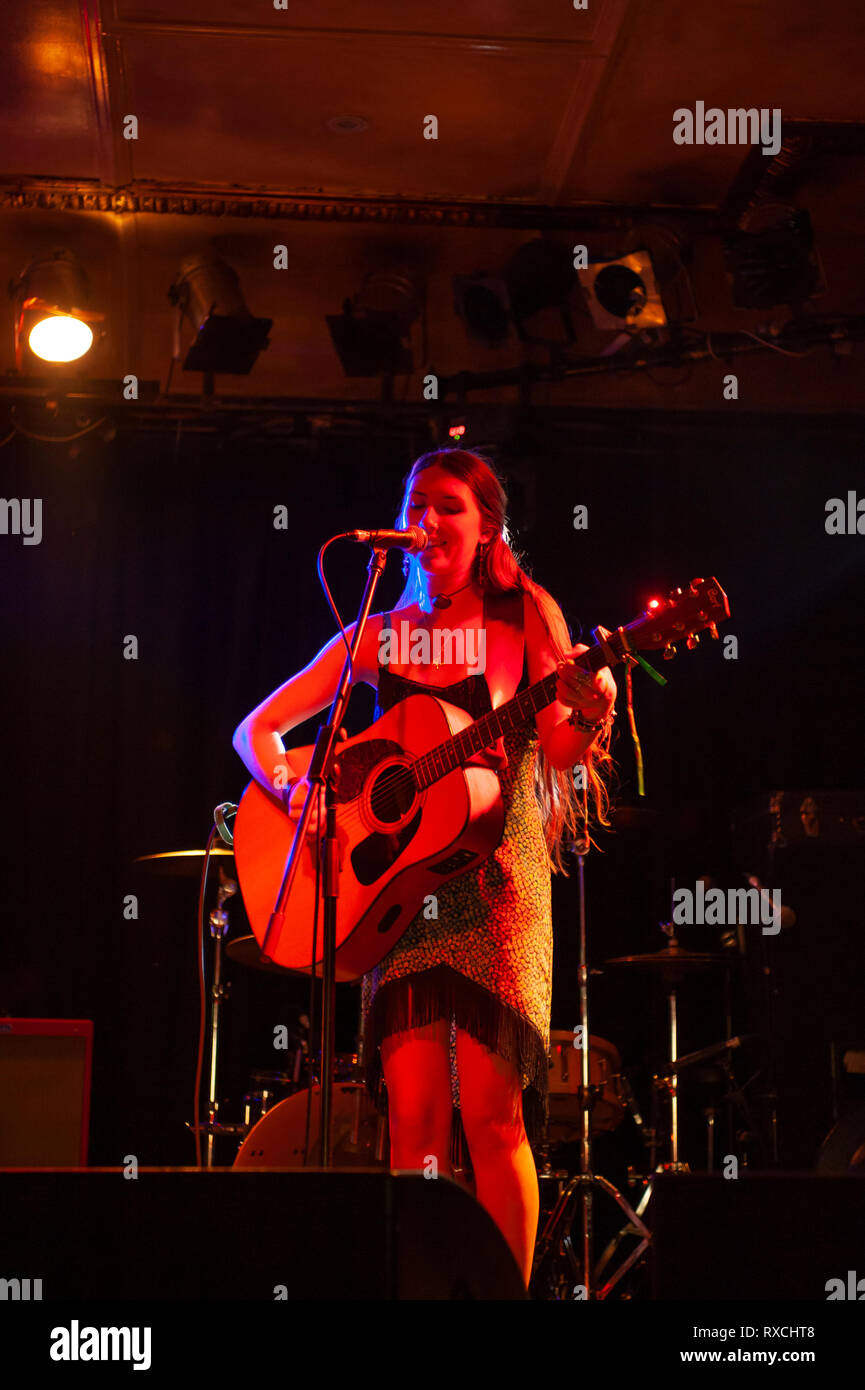 Cantante femminile con la chitarra acustica suonare sul palco Foto Stock