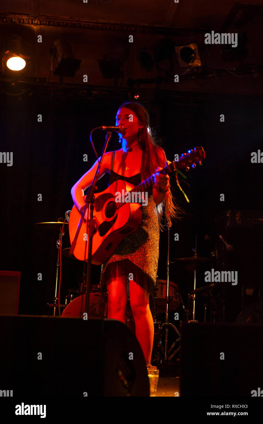 Cantante femminile con la chitarra acustica suonare sul palco Foto Stock