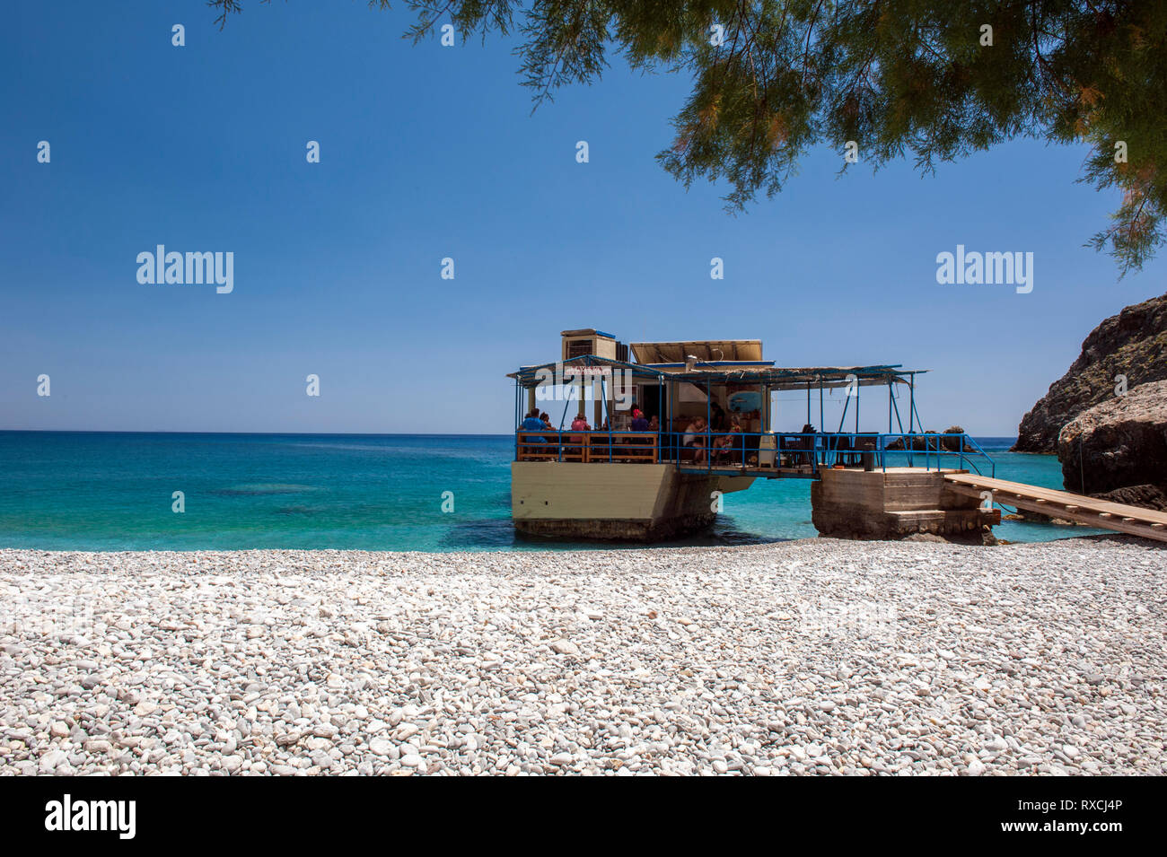 Una taverna costruita su rocce nel mare a Sweetwater Beach, tra Hora Sfakion e Loutro sulla costa meridionale di Creta. Foto Stock