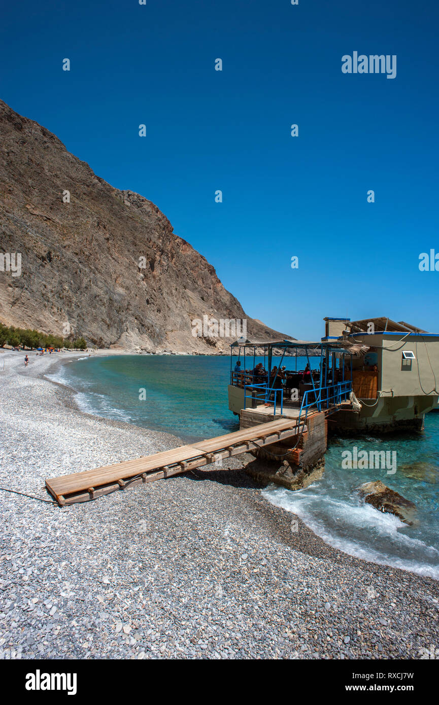 Una taverna costruita su rocce nel mare a Sweetwater Beach, tra Hora Sfakion e Loutro sulla costa meridionale di Creta. Foto Stock