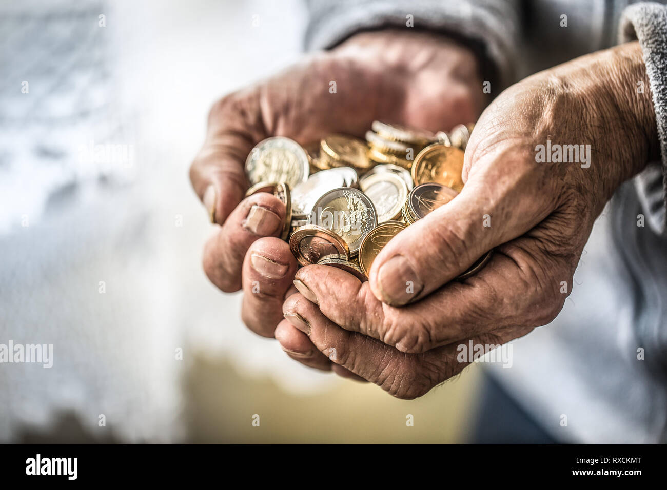 Titolare di pensione o di rendita uomo tenendo in mano delle monete in euro. Il tema delle pensioni basse Foto Stock