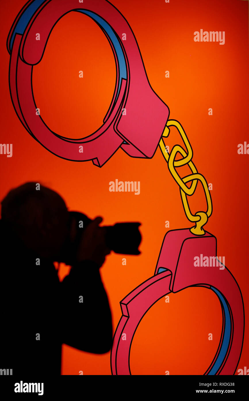 Londra, Regno Unito. 8 Mar 2019. Un fotografo si profila davanti di artwork, precedentemente di proprietà della cantante-cantautore George Michael, "manette' da Michael Craig-Martin (dietro) a casa d'aste Christie's di Londra, Regno Unito, Venerdì, Marzo 08, 2019. Il pezzo fa parte di George Michael serata di raccolta e asta online la prossima settimana. Esso è stimato per ottenere un prezzo massimo di 50.000 sterline rispettivamente fotografia : © Luca MacGregor Credit: Luke MacGregor/Alamy Live News Foto Stock