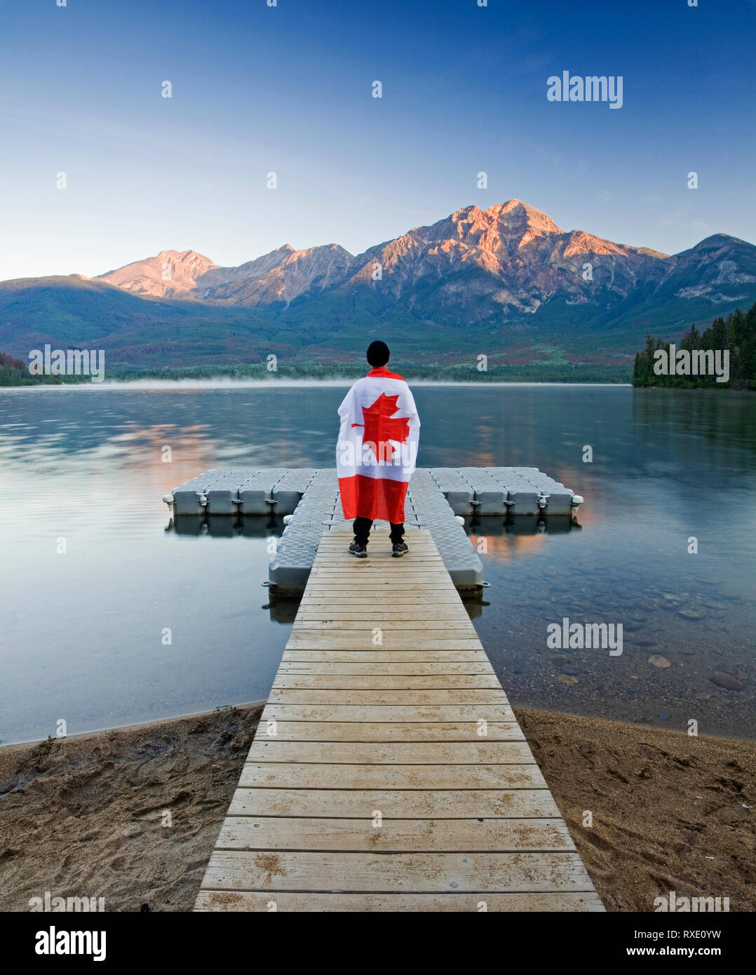 Maschio con bandiera canadese passeggiate su una banchina sul Lago Piramide, il Parco Nazionale di Jasper, Alberta, Canada. Foto Stock