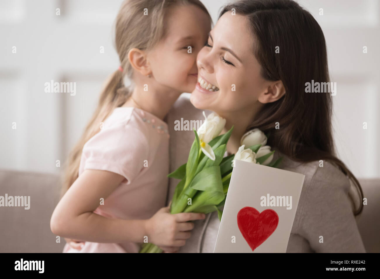 Figlia di capretto azienda fiori kissing congratularmi con la mamma con la festa della mamma Foto Stock
