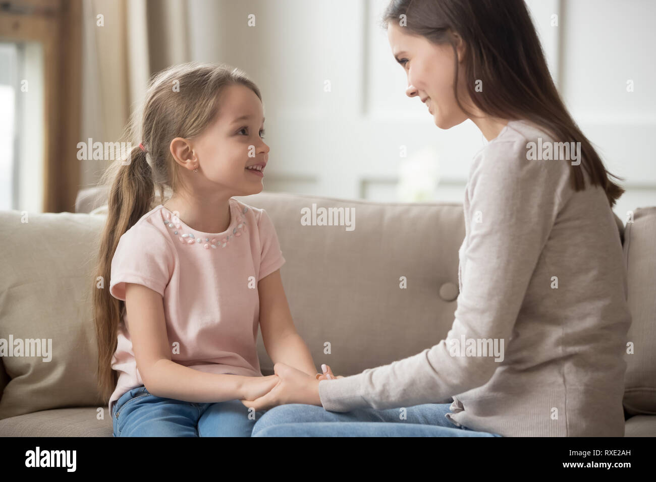 Amare la madre e il bambino per mano di parlare seduto sul divano Foto Stock
