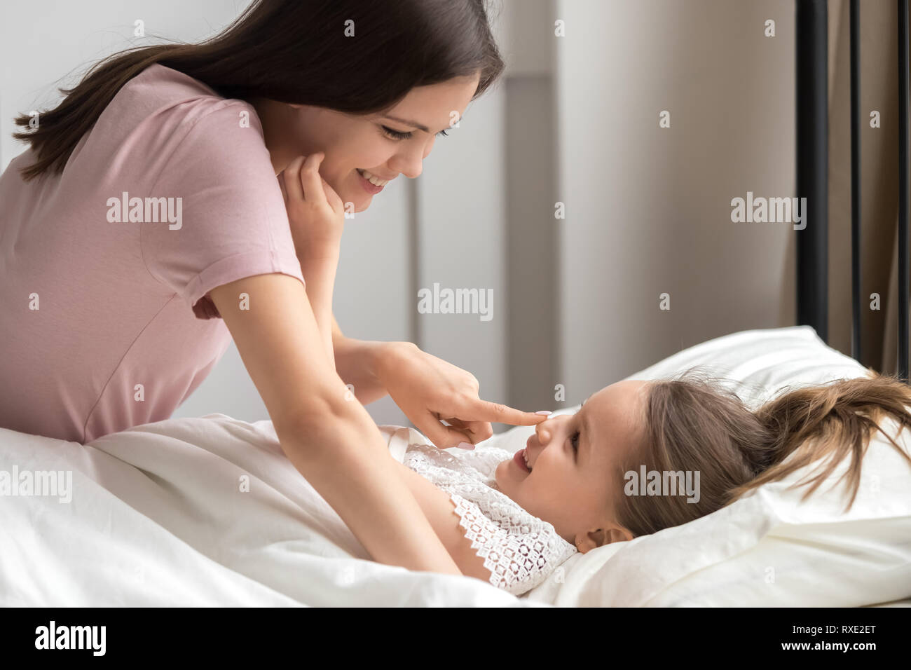 Felice madre teneramente il risveglio carino kid figlia a letto Foto Stock