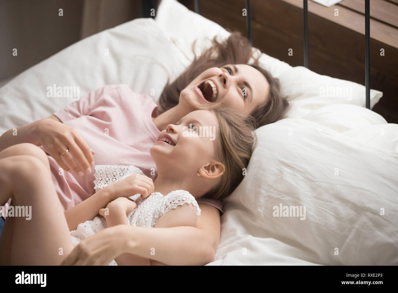 La famiglia felice madre abbracciando kid figlia ridere giacente sul letto Foto Stock