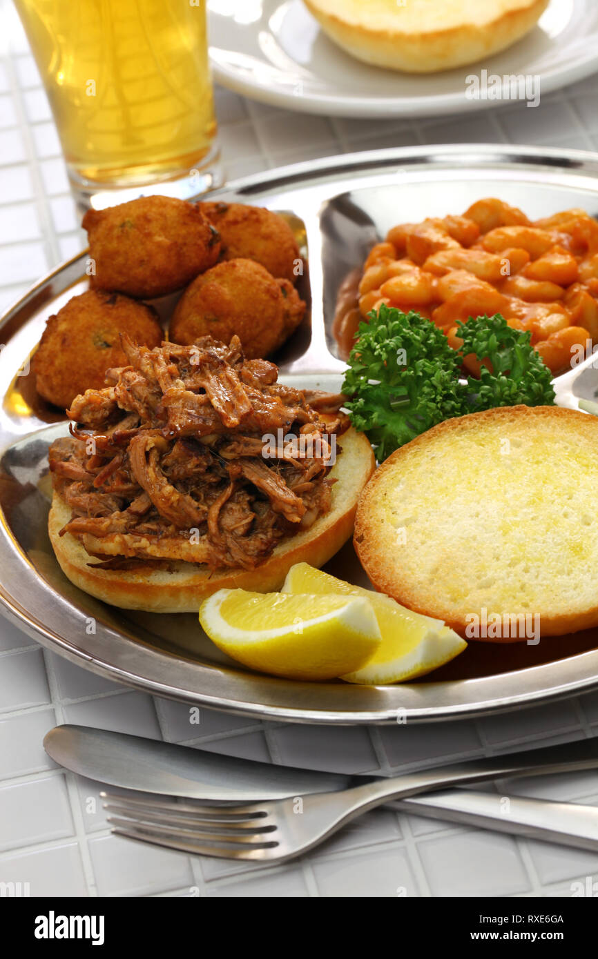 North Carolina piastra barbecue ; tirata di maiale, frittelle di farina di mais, fagioli al forno e coleslaw Foto Stock
