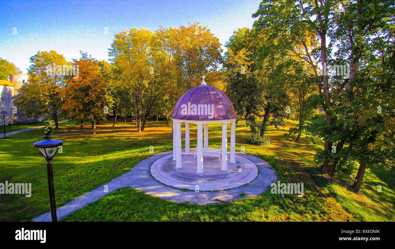 Il pergolato o gazebo nel cortile erboso con alberi che circondano il parco e un banco all'interno di the bower Foto Stock