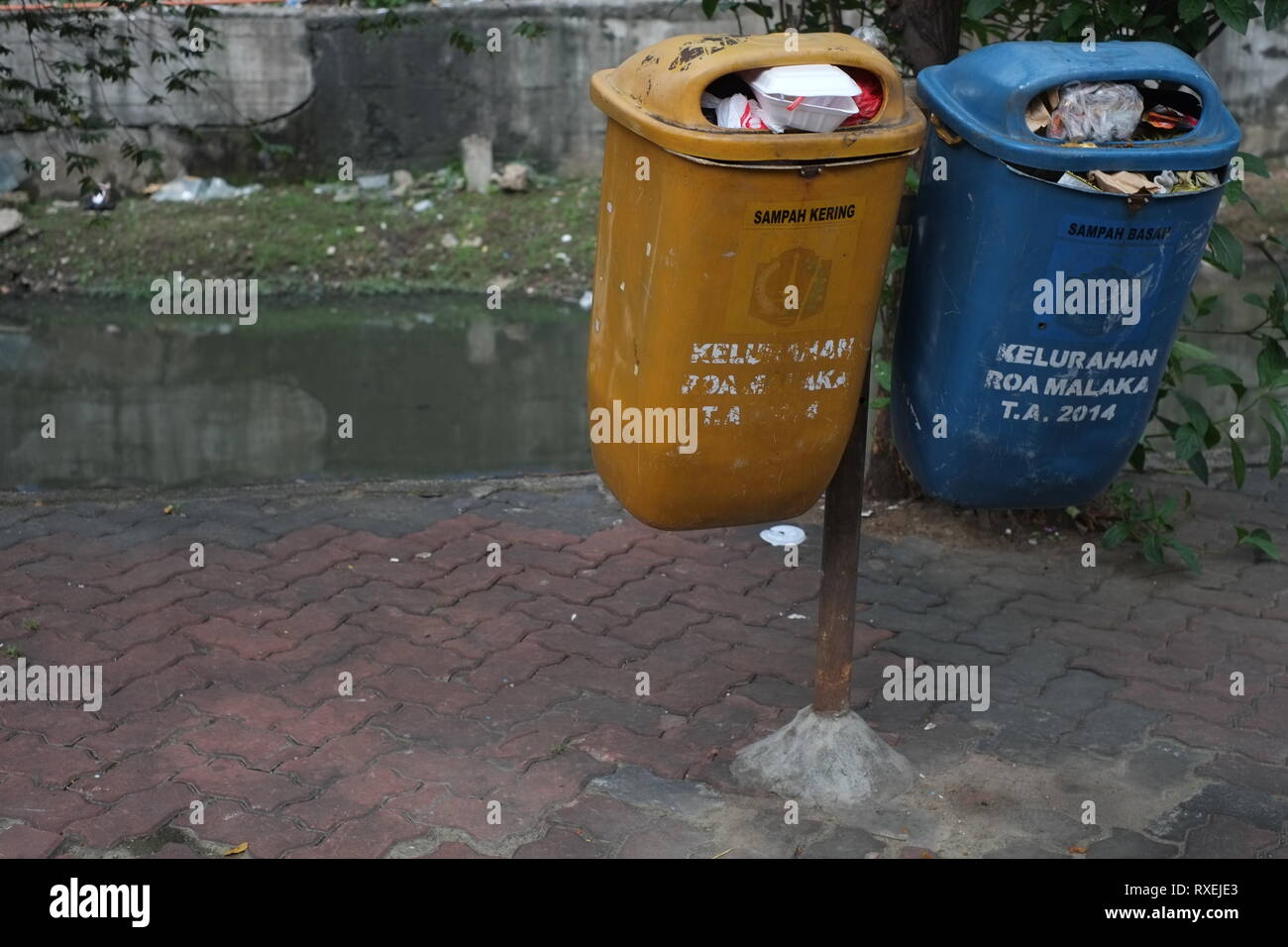 Due cestini di plastica pieni in un posto pubblico accanto ad un fiume a Jakarta, Indonesia. Foto Stock