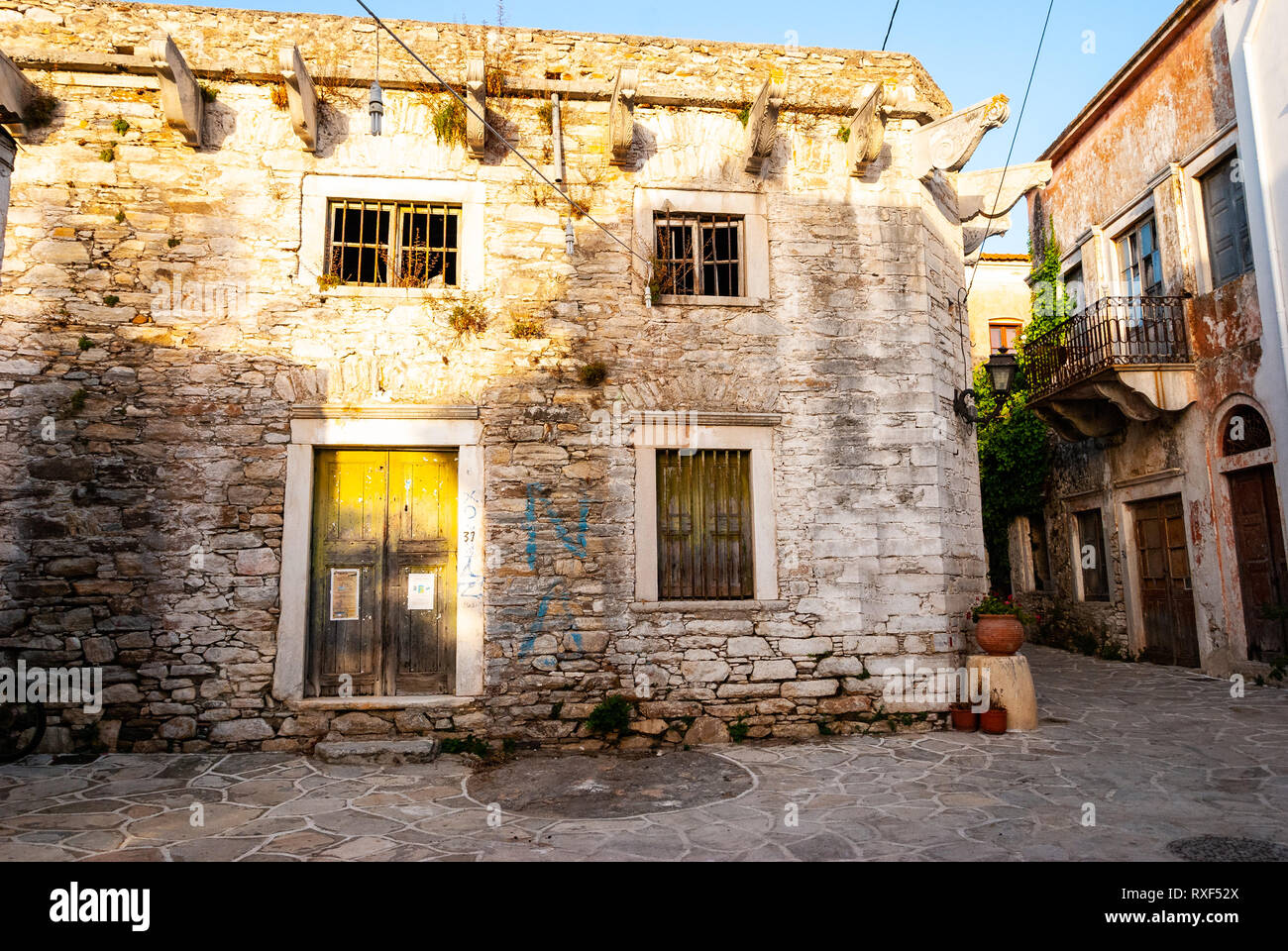 Una vecchia casa e un vicolo immerso nella luce del sole dorato in Grecia Foto Stock