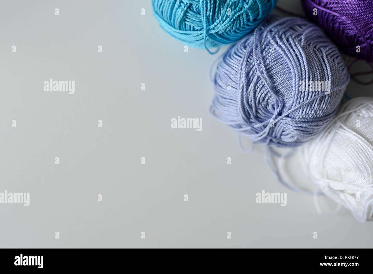 Viola, Blu e bianco filato per maglieria di sfere per l'artigianato nell'angolo dell'immagine come una decorazione sopra copiare lo spazio bianco su sfondo tabella. Foto Stock