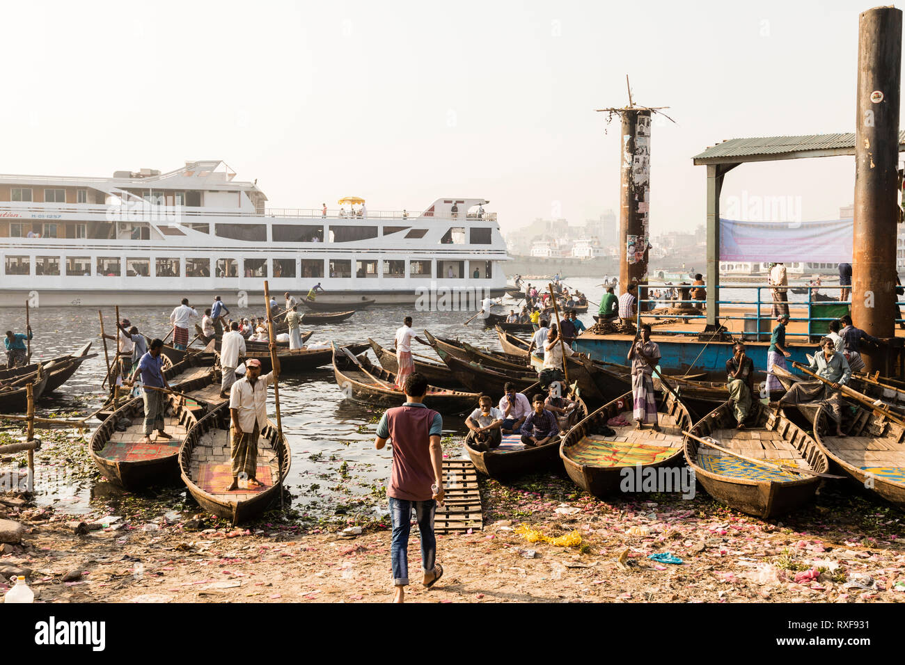 Dacca in Bangladesh, 24 Febbraio 2017: piccole imbarcazioni a remi servono come taxi tra le due sponde del fiume sul fiume Buriganga a Dacca in Bangladesh, in backg Foto Stock