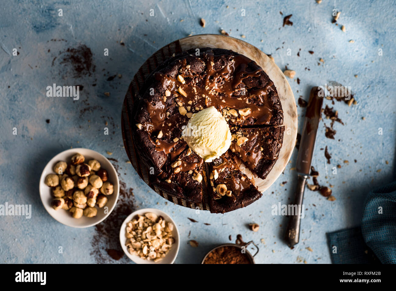 Torta al cioccolato con una pallina di gelato alla vaniglia su un piatto rotondo con nocciole tritate Foto Stock