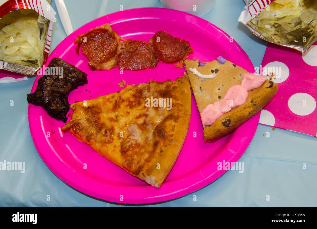 Festa di compleanno del cibo con un morso preso dalle delizie assortite inclusa pizza, patatine, biscotti e torte brownie. Foto Stock