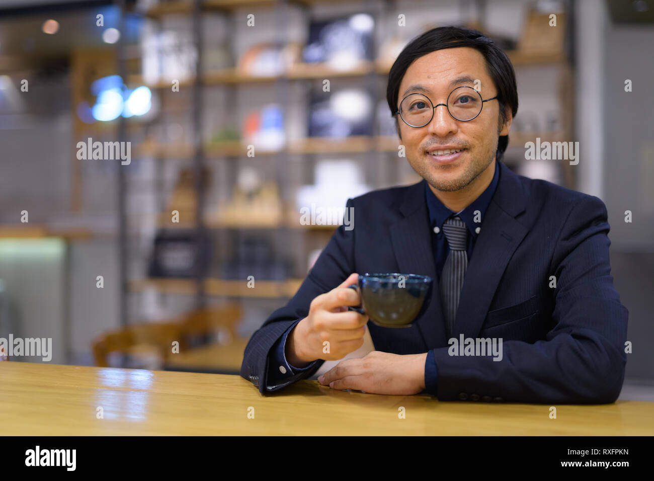 Happy businessman asiatica di bere il caffè all'interno del coffee shop Foto Stock