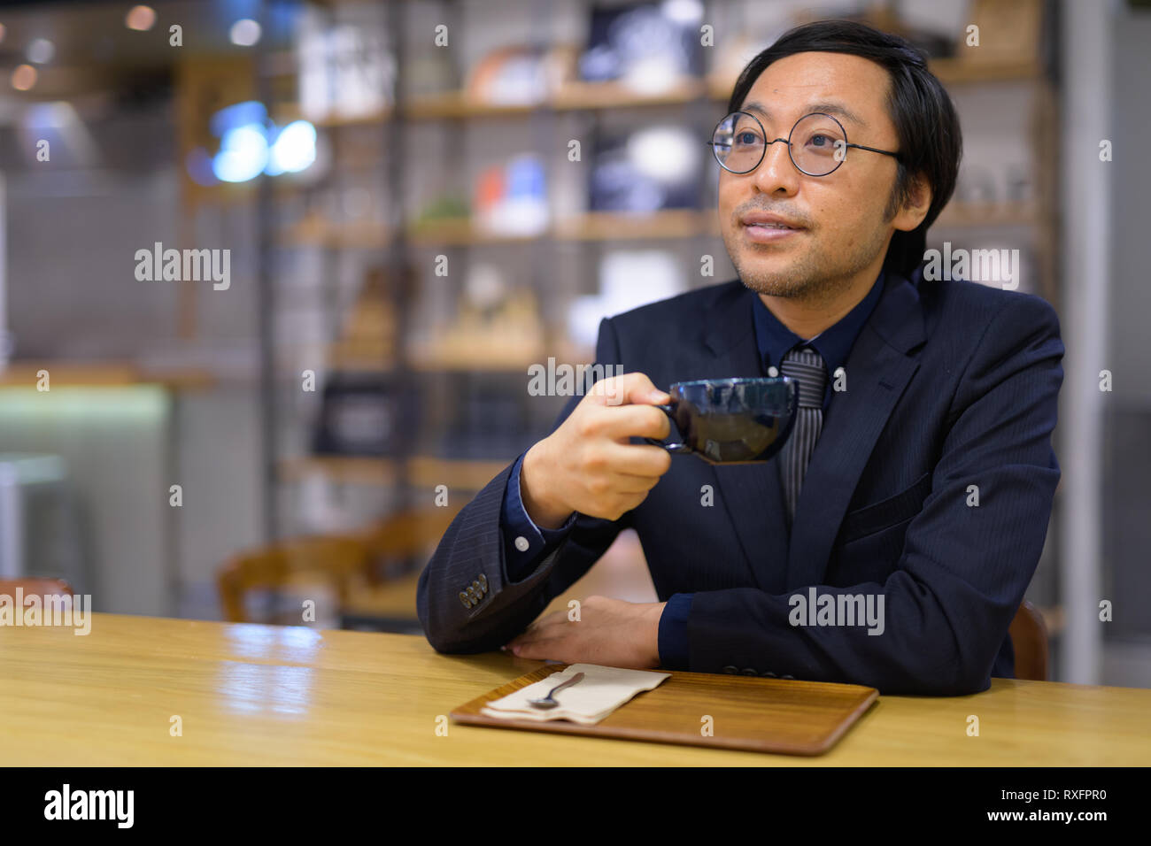 Happy businessman asiatici pensare mentre si beve il caffè Foto Stock